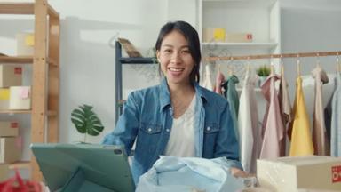年轻的亚洲女士时装设计师使用手机接收订购单，并在商店网上直播服装录像。小<strong>企业</strong>主，网<strong>上市</strong>场交付概念.